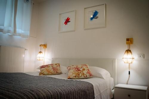 a bedroom with a bed with two pillows and two lights at Lake House in Nago-Torbole