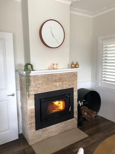 a living room with a fireplace with a clock on the wall at Armara Views in Orange