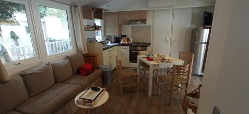 un salon et une cuisine avec un canapé et une table dans l'établissement KOKUA VACANCES Mobil Homes Résidentiels camping 4 étoiles Saint Cyprien, à Saint-Cyprien