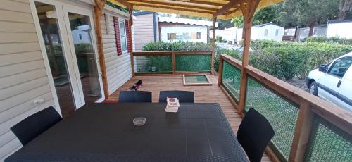une véranda avec une table et des chaises noires dans l'établissement KOKUA VACANCES Mobil Homes Résidentiels camping 4 étoiles Saint Cyprien, à Saint-Cyprien