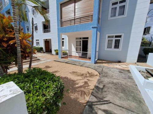 a white building with a palm tree in front of it at Soleil Vacances Loisirs in Flic-en-Flac