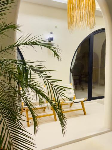 a room with a bench and a palm tree at Casa Del La Luna by Nginapsini in Cilama