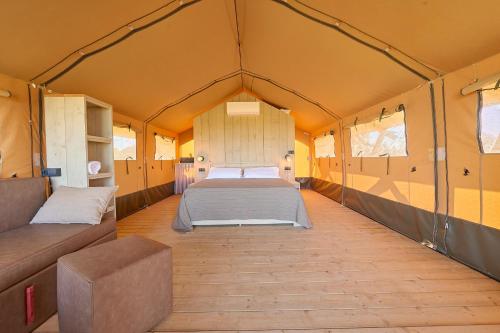 a large tent with a bed and a couch in it at Delfino Tuscany Resort in Marina di Cecina