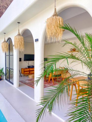 a living room with white walls and a palm tree at Casa Del La Luna by Nginapsini in Cilama
