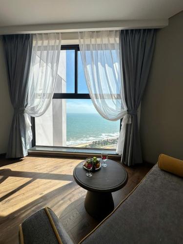 a living room with a table and a large window at Apec Mandala Muine in Mui Ne