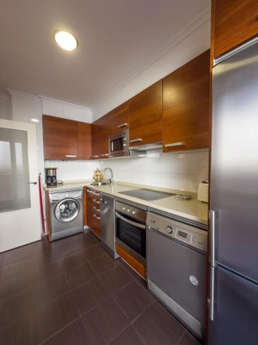 a kitchen with stainless steel appliances and wooden cabinets at Apartamentos Verdemar (VUT) in Llanes