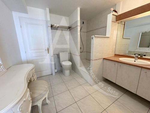 une salle de bain blanche avec des toilettes et un lavabo dans l'établissement Sur les hauteurs, T4 avec clim, wifi, parking et piescine, à Sète
