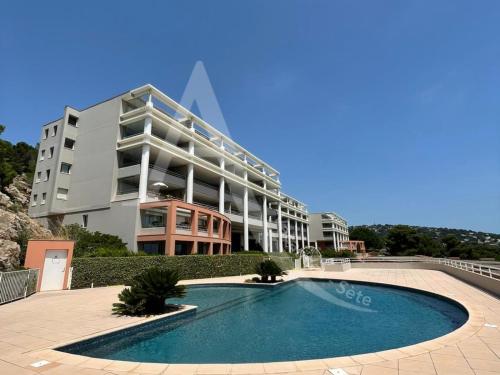 un immeuble avec une piscine devant un immeuble dans l'établissement Sur les hauteurs, T4 avec clim, wifi, parking et piescine, à Sète