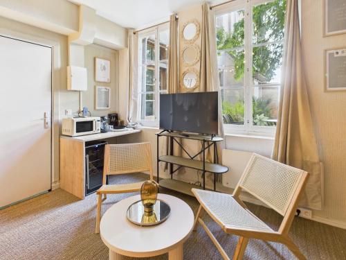 - un salon avec des chaises, une table et une télévision dans l'établissement Tulum - Spa & Voyage, à Troyes