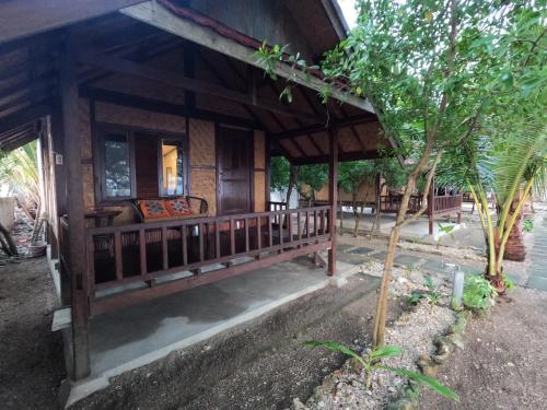 a wooden house with a porch and a tree at Maryan Moyo Bungalows & Resto in Moyo Island
