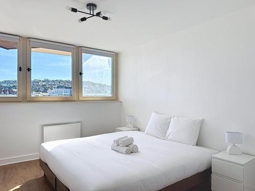 - une chambre avec un grand lit blanc et 2 fenêtres dans l'établissement Les Voiles YourHostHelper, à Deauville