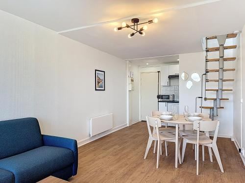 - un salon avec une table à manger et un canapé bleu dans l'établissement Les Voiles YourHostHelper, à Deauville