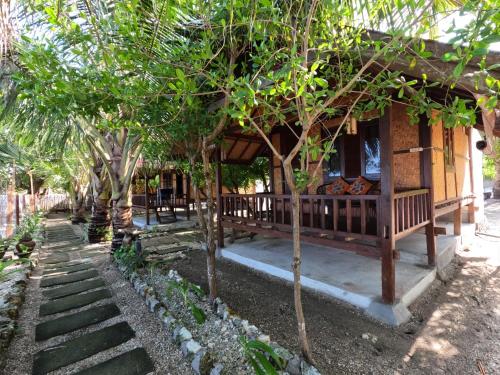 a house with trees in front of it at Maryan Moyo Bungalows & Resto in Moyo Island