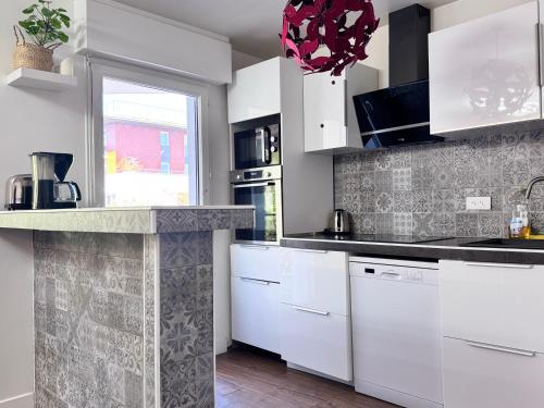 une cuisine avec des armoires blanches et une fenêtre dans l'établissement FRUITIERS2 - Bright 3 BR 15' away from the center of Paris, à Saint-Denis