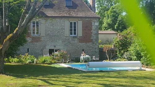 une personne assise devant une maison avec une piscine dans l'établissement Mas de Fantou, à Anglars-Juillac