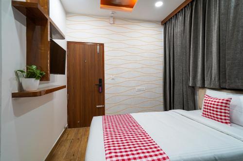 a bedroom with a bed with a red and white checkered blanket at Open Hotel by Olive - Ejipura in Bengaluru