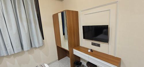a living room with a tv and a mirror at Hotel Nexus Inn in Ahmedabad
