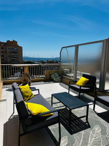 un balcon avec des coussins jaunes et des chaises sur un toit dans l'établissement La Marine' Hyères, à Hyères