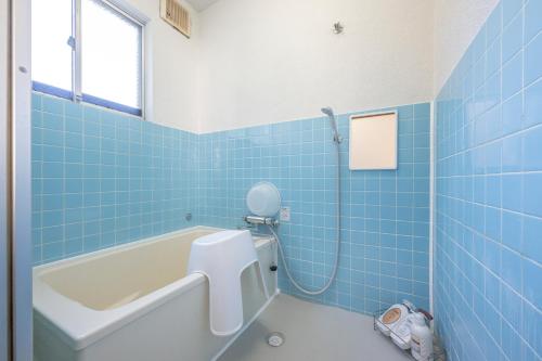 a blue tiled bathroom with a tub and a toilet at 最大9名可 無料駐車場付 和モダン1棟貸切 4独立寝室 乾燥機付 in Gifu