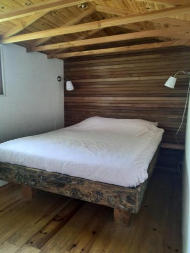 una cama en una habitación con techo de madera en Chalet l 'Hirondelle Le Petit Montperroux, en Saint-Didier-sur-Arroux