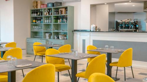a dining room with tables and yellow chairs at AHG Riva Del Sole Hotel - Adults Only in Moniga