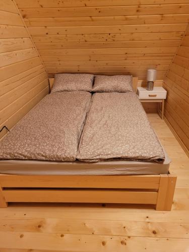 a bed in a wooden cabin with a night stand at Domki na Bukowinie in Węgierska Górka