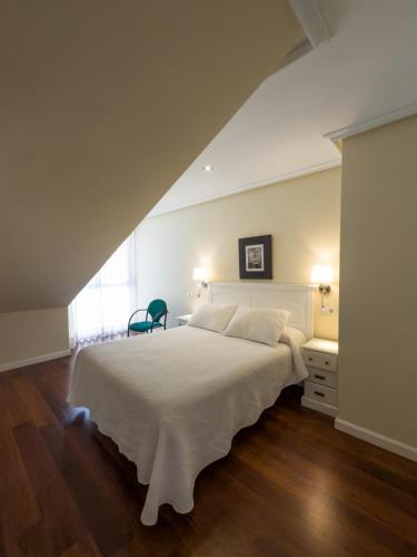 a bedroom with a large white bed and a chair at Apartamentos Verdemar (VUT) in Llanes