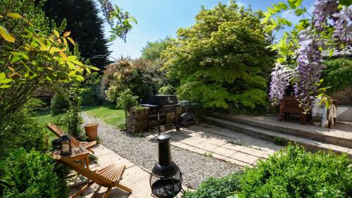 a garden with a grill and chairs and trees at Honeywick Cottage in Stow on the Wold