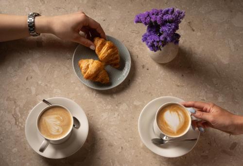 a person holding a cup of coffee and two plates of food at Mitsis N'U Piraeus Port in Piraeus