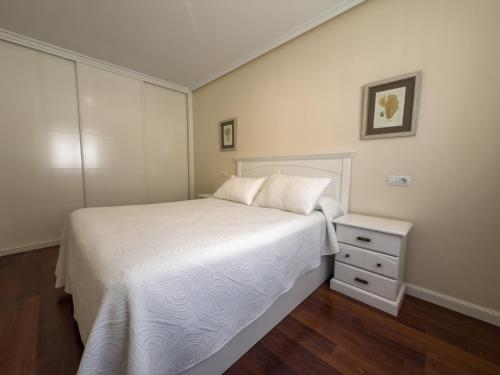 a bedroom with a white bed and a night stand at Apartamentos Verdemar (VUT) in Llanes
