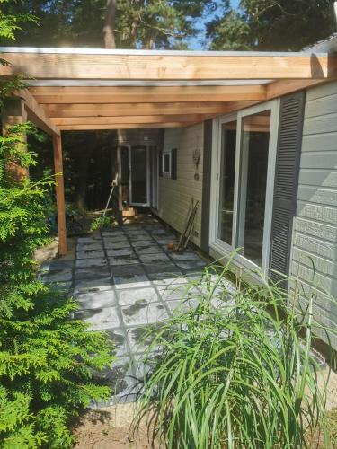a patio with awning on the side of a house at Tiny house in bos bij Veluwezoom rust en comfort in Hattemerbroek