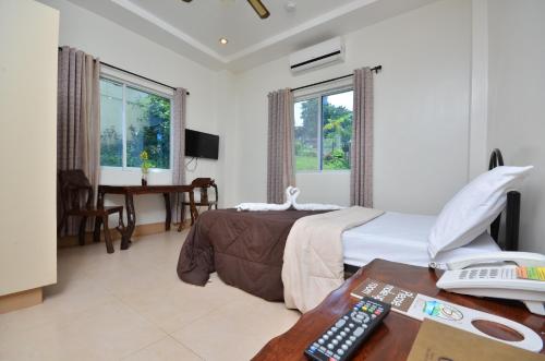 - une chambre avec un lit et un bureau avec un ordinateur dans l'établissement Villa de Sierra Vista Bay and Mountain View Inn, à Puerto Princesa