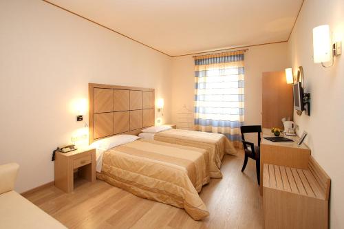 Hotel Roma في ترييستي: غرفه فندقيه بسرير ونافذه