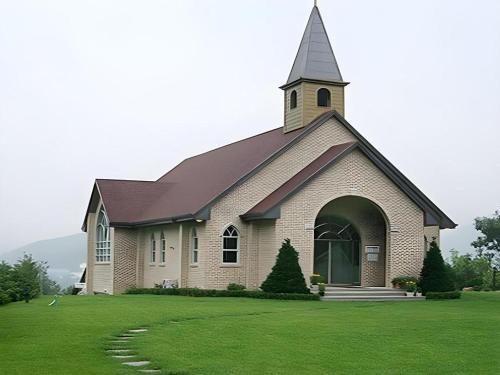 a church with a steeple on a green lawn at Suanbo Park Hotel in Suanbo
