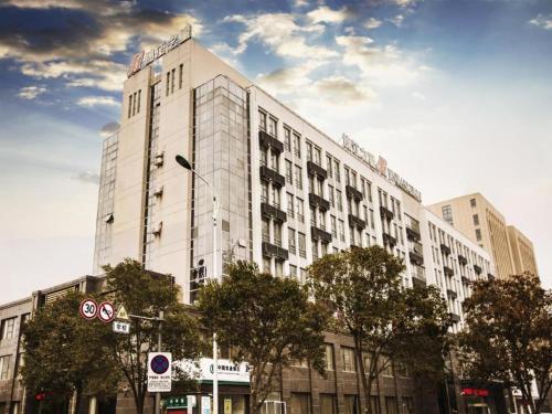 a large white building with trees in front of it at Jinjiang Inn Yancheng Funing Harbin Road in Yancheng