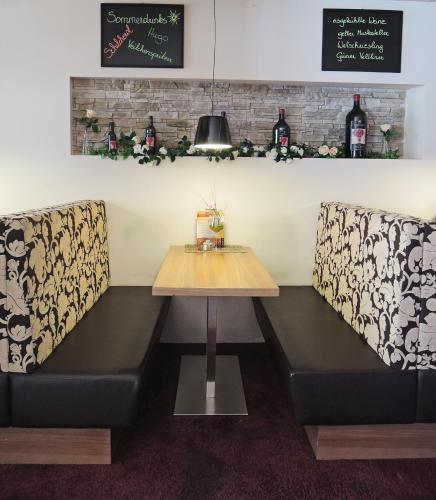 a table and two booths in a restaurant with wine bottles at Pension Central in Markt Piesting
