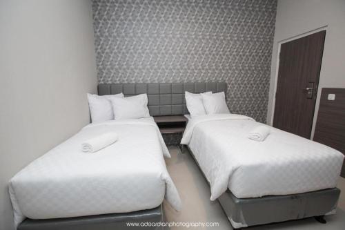 two beds in a hotel room with white sheets at Smart Budget Hotel in Semarang