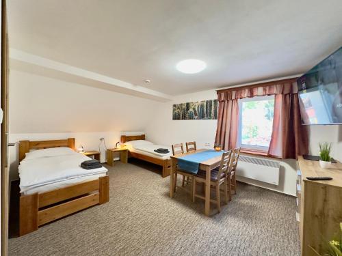 a room with two beds and a desk and a table at Ubytování Smrk in Nové Město pod Smrkem