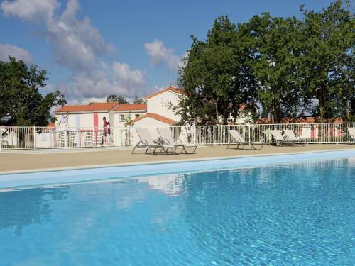 - une piscine avec des chaises en face d'un bâtiment dans l'établissement Cozy Holiday Home Near Veillon, à Saint-Hilaire-de-Talmont