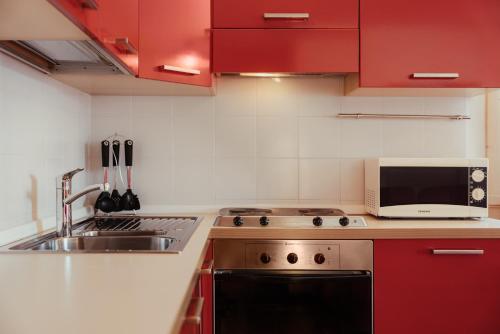 a kitchen with red cabinets and a sink and a microwave at Stella Due in Arabba