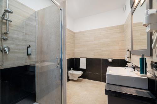 a bathroom with a shower and a sink and a toilet at Bellevue Sardinia Resort Affiliated by Meliá in Valledoria