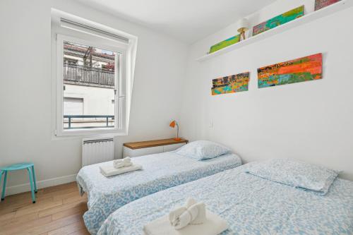 deux lits dans une chambre avec une fenêtre dans l'établissement Nice apartment in the heart of Paris by Weekome, à Paris