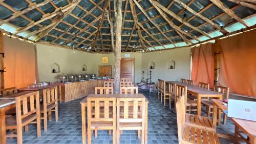 a dining room with wooden tables and chairs at CampKelang Bir Luxury Tents in Bir Billing in Bīr
