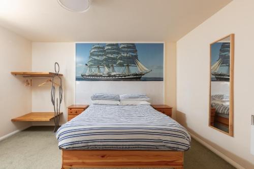 a bedroom with a bed with a painting of a ship at Discovery Accommodation in Whitby