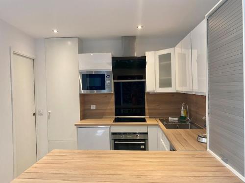 une cuisine avec des armoires blanches et des appareils noirs dans l'établissement Le Cosy- Terrasse et centre ville, à Annecy