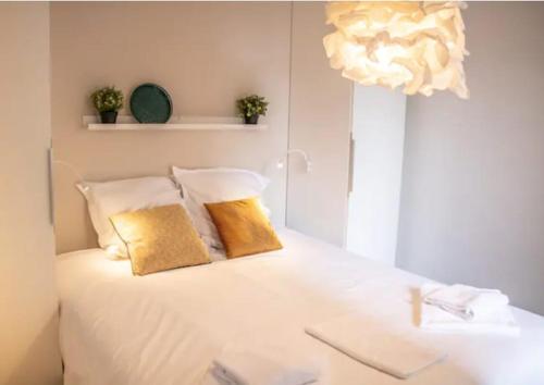 - un lit blanc avec 2 oreillers jaunes dans l'établissement Le Cosy- Terrasse et centre ville, à Annecy