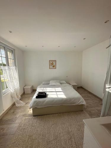 une chambre blanche avec un grand lit et une fenêtre dans l'établissement maison dans la Prairie, à Lhomme