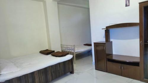 a room with two beds and a dresser in it at Krushnakunj Holiday Resort, Nagaon in Alibaug