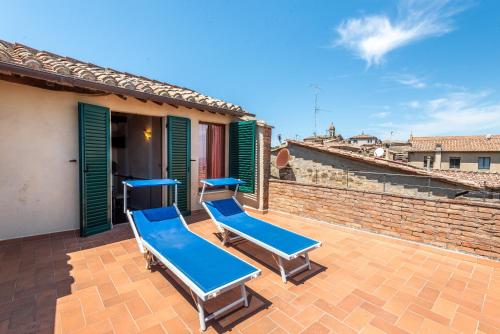 a patio with two blue lounge chairs on a roof at beb del Musico in Montalcino