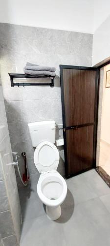 a bathroom with a toilet and a wooden door at Green House Stay in Mandrem